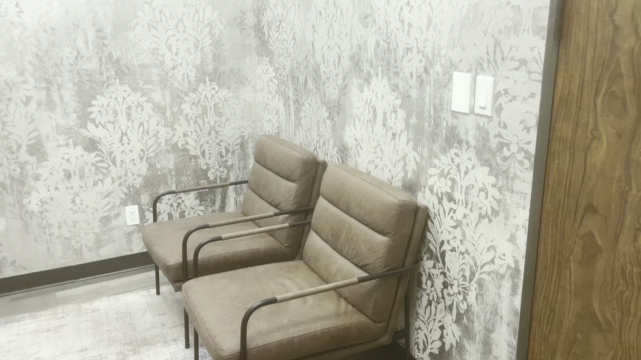 Two waiting chairs against the patterned wall by the reception door at our clinic