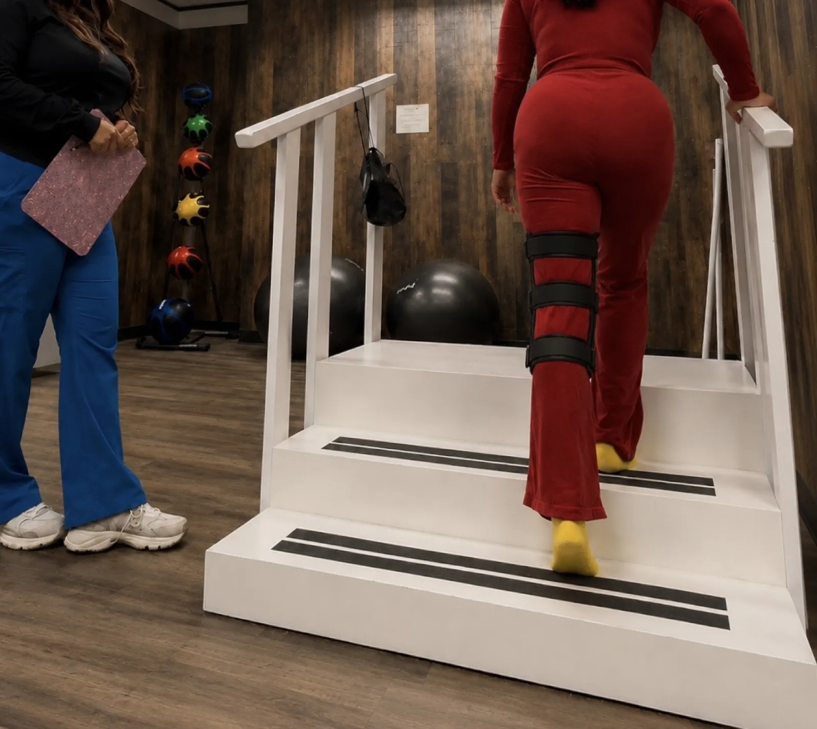 A patient practicing the training stairs with a therapist beside her at our clinic